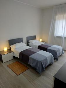 two beds in a white room with two lamps at Novatek Apartment B&B in Chieti