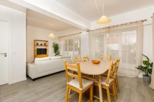 a dining room with a table and chairs and a couch at Villas Boas House Caparica in Costa da Caparica
