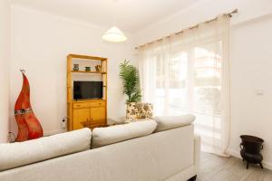 a living room with a white couch and a tv at Villas Boas House Caparica in Costa da Caparica