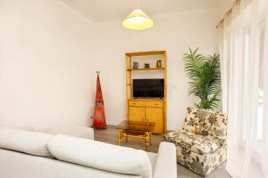 a living room with a couch and a tv at Villas Boas House Caparica in Costa da Caparica