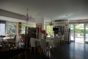 une salle à manger avec des tables et des chaises blanches et un lustre dans l'établissement Hotel Anapaya, à Lignano Sabbiadoro