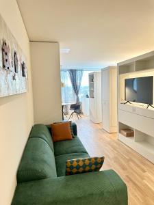 sala de estar con sofá verde y TV en MydiHei @ Rhyfall Towers, en Neuhausen am Rheinfall