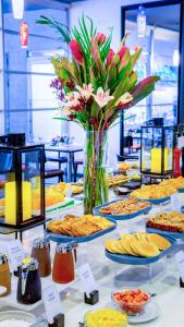 a table filled with different types of pastries and a vase of flowers at NH Collection Medellin Royal in Medellín