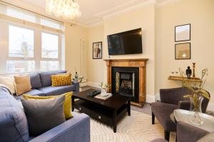 a living room with a blue couch and a fireplace at The Peckham Hideaway - Bright 3BDR Flat in London