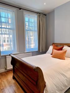 a bedroom with a large bed with two windows at Spacious Belsize Park apartment close to station in London