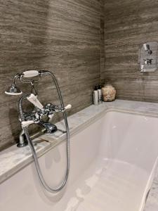a bath tub with a faucet in a bathroom at Spacious Belsize Park apartment close to station in London