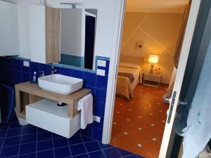 a blue tiled bathroom with a sink and a bed at La casetta del poggio in Poggio a Caiano +5 photos