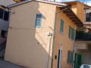 a building with green shutters on the side of it at La casetta del poggio in Poggio a Caiano