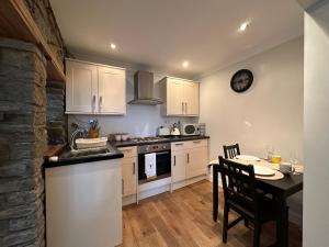 a kitchen with white cabinets and a table and a sink at The Cosy Cottage Retreat! Perfect for Contractors, Relocators, Getaway in Llantrisant