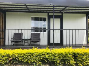 two chairs and a table on the porch of a house at Hotel & Golf Isak Aeropuerto in Rionegro