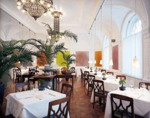 a restaurant with tables and chairs and a chandelier at Parkhotel Laurin in Bolzano