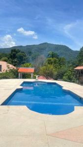 ein großer blauer Pool mit einem Berg im Hintergrund in der Unterkunft Apartamento con piscina en jarabacoa in Jarabacoa