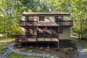 a small yellow house with a porch and balcony at The Green Forest Retreat - Kayak, Hot Tub, Sauna in East Stroudsburg