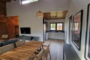a living room with a wooden table and a kitchen at Domek na Cyplu Ostrowskim in Ostrowo