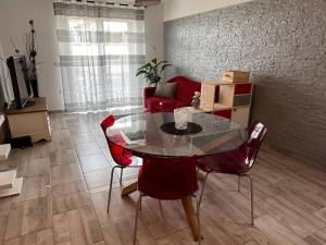 sala de estar con mesa de cristal y sillas rojas en Casa Relax Immersa Nel Verde, en Manzano