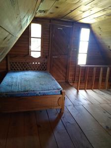 Cama en habitación de madera con 2 ventanas en La morada del amigo, en La Trinitaria