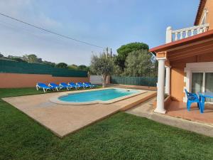 una piscina con sillas azules y una casa en Costa Brava Suites Villa Cèsar, en Calonge