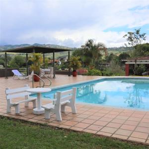 uma mesa e bancos ao lado de uma piscina em Finca cerca a Cali - Pura Naturaleza - El Carmen, Colombia em Papagalleros