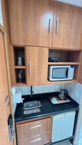a small kitchen with a microwave and a sink at Flat no Condomínio do Edifício Tropical Executive e residence com Vista para o Rio in Manaus