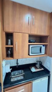 eine Küche mit einer Spüle und einer Mikrowelle in der Unterkunft Flat no Condomínio do Edifício Tropical Executive e residence com Vista para o Rio in Manaus