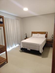 a bedroom with a white bed and a large window at Residencial ponta do sol in Capitólio +31 photos
