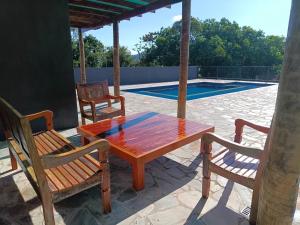 a wooden table and chairs on a patio with a pool at Residencial ponta do sol in Capitólio