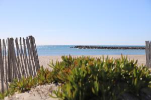 a beach with a fence and some plants and the ocean at T2 La Dolce Vita Accès Privé Plage Palavas in Palavas-les-Flots