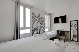 a white bedroom with two beds and a desk and a window at Modern's Hotel in Paris