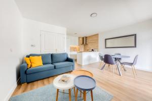 uma sala de estar com um sofá azul e uma mesa em Cosy appartement Proche Disneyland Paris em Montévrain