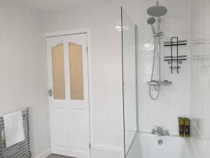 a white bathroom with a shower and a sink at Lenny House in Bradshaw