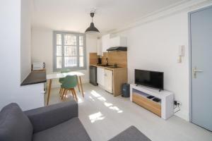 a living room with a couch and a tv and a kitchen at Le Triompha Montpellier Proche Arc de Triomphe in Montpellier