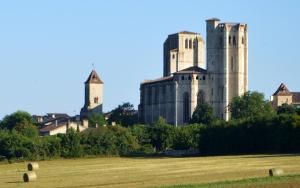 un ancien château avec deux tours dans un champ dans l'établissement La Chambre des Marronniers, à La Romieu
