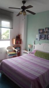 a bedroom with a purple bed and a ceiling fan at Apartamento playa Muchavista in El Campello