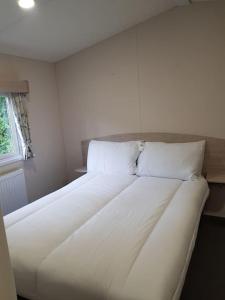 ホルズワージーにあるDelightful Modern Two Bedroom Static Caravanの窓付きの客室で、白い大型ベッド1台が備わります。