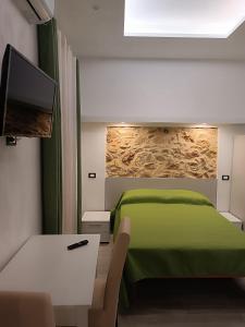 1 dormitorio con 1 cama verde y TV de pantalla plana en Real, en Marina di Camerota