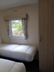 ホルズワージーにあるDelightful Modern Two Bedroom Static Caravanのベッドと窓が備わる小さな客室です。