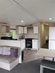ホルズワージーにあるDelightful Modern Two Bedroom Static Caravanの白いキャビネットとソファ付きのキッチンが備わります。