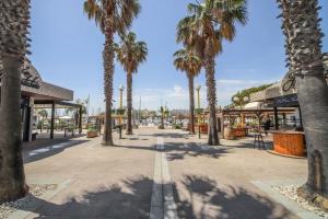 a street with palm trees in front of a building at Le Bella Vista Vue Port Carnon Proche Plage in Mauguio