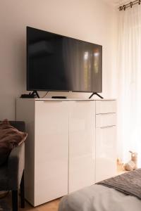Apartment City Cat في Križevci: تلفزيون على رأس خزانة بيضاء في غرفة النوم