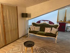uma sala de estar com um sofá verde com almofadas em B&B Villa Alma em San Cristoforo de Valli