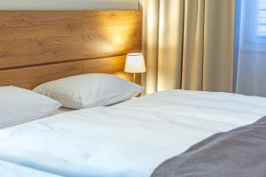 1 dormitorio con 2 camas blancas y cabecero de madera en NOVY Hotel, en Zielona Góra