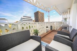 Un balcón con 2 sillas y una terraza de madera. en Grand T2 Montpellier Climatisation Terrasse Proche centre Ville et Plages en Montpellier