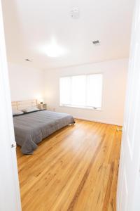 a white bedroom with a bed and a wooden floor at Elegant & Spacious 3-bed Gem mins to NYC in Jersey City