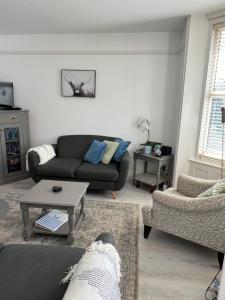 a living room with a couch and a table at Sea Salt Cottage - Mins to beach & shops Dog Friendly in Deal