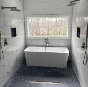 uma banheira branca na casa de banho com uma janela em The Getaway House ATL em Carrollton