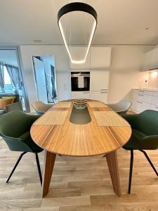 una mesa de madera en una cocina con sillas verdes en 3.5Room@MydiHei Apartments, en Neuhausen am Rheinfall