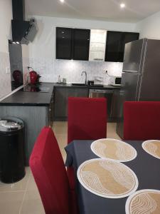 eine Küche mit roten Stühlen, einem Tisch und einem Kühlschrank in der Unterkunft Gîte en Corrèze 12 pers, Piscine chauffée et Salle de jeux in Chamboulive