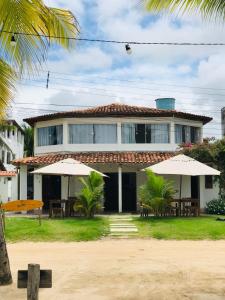 a house with tables and umbrellas in front of it at Pousada Enero in Maragogi