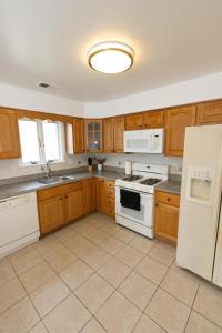 a kitchen with wooden cabinets and white appliances at Elegant & Spacious 3-bed Gem mins to NYC in Jersey City