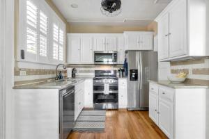 cocina con armarios blancos y nevera de acero inoxidable en Lush 4BR on Lincoln, en Columbia